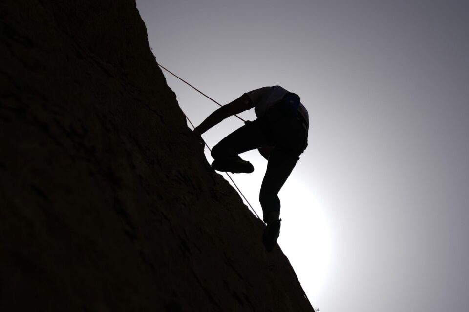 Editorial cover art for a rock climbing training plan showing a climber silhouette, chalk dust, and a hangboard on a clean grid background