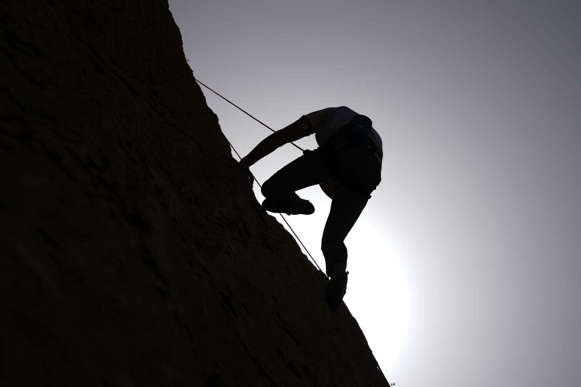 Editorial cover art for a rock climbing training plan showing a climber silhouette, chalk dust, and a hangboard on a clean grid background