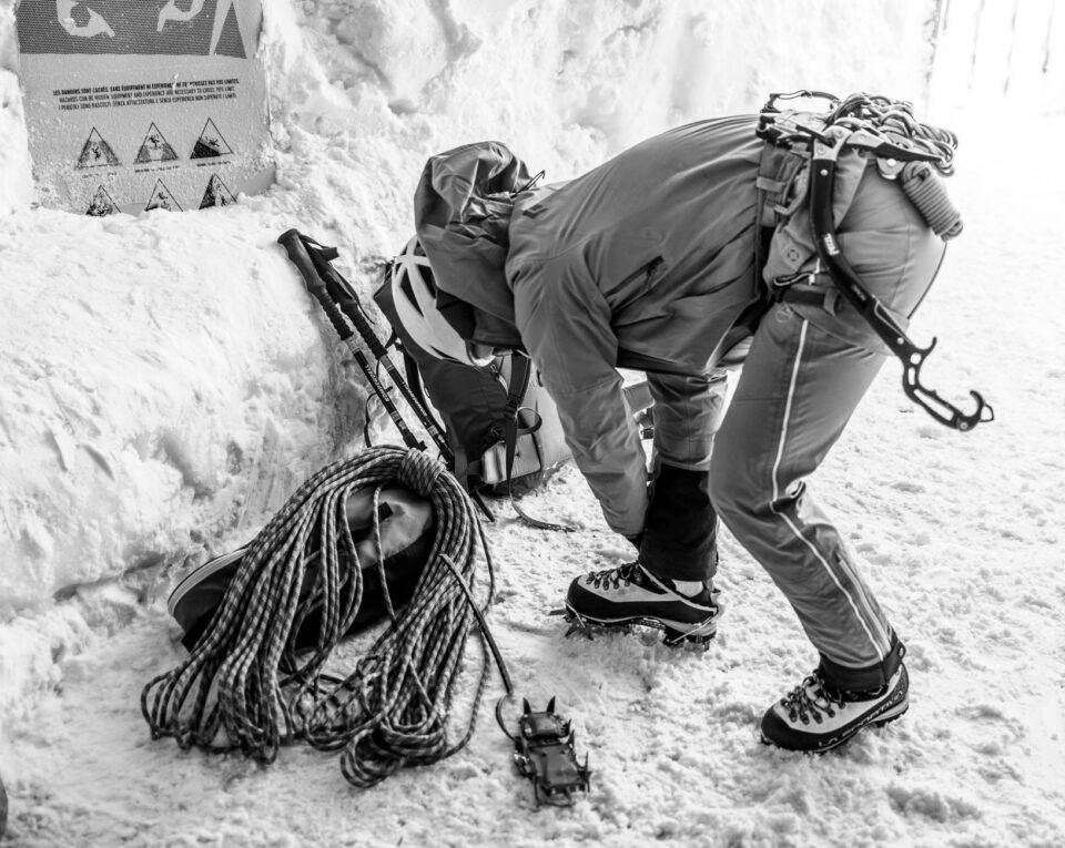 Illustrated mountaineering gear checklist cover showing boots, rope, helmet, ice axe, and layered clothing laid out on a tarp